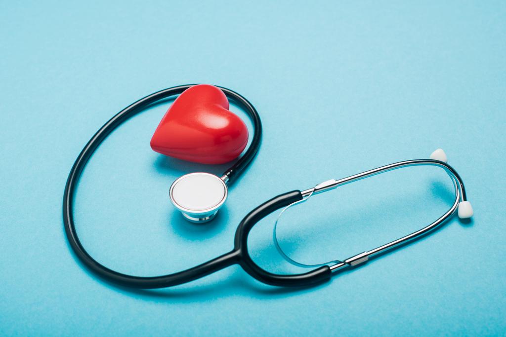 Coração vermelho decorativo e estetoscópio no fundo azul, conceito de dia de saúde mundial
 - Foto, Imagem