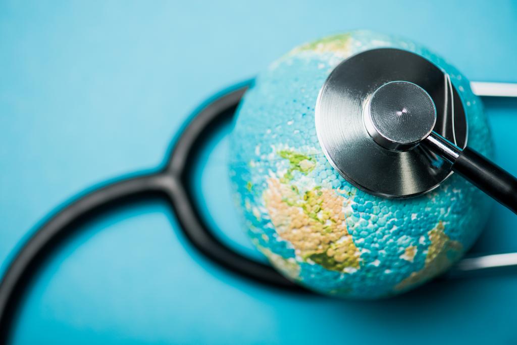 Stetoskoopin selektiivinen painopiste, joka liittyy maapalloon sinisellä taustalla, maailman terveyspäivän käsite
 - Valokuva, kuva