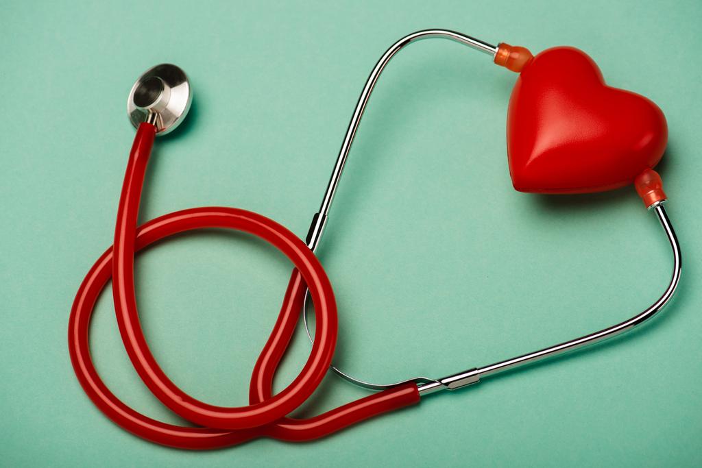 Červený stetoskop a dekorativní srdce na zeleném pozadí, koncept světového dne zdraví - Fotografie, Obrázek