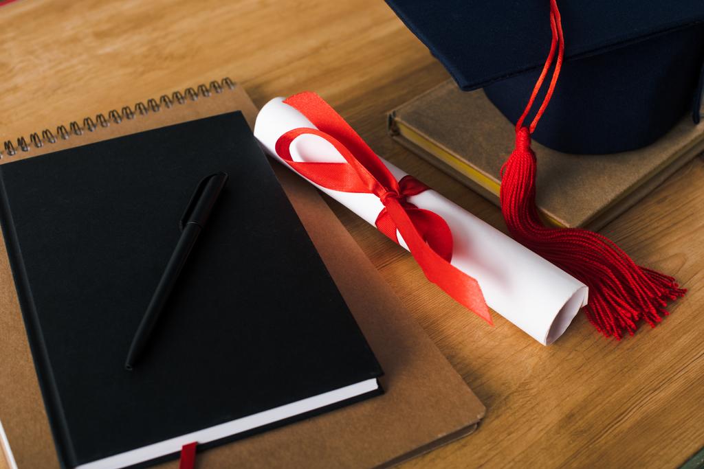 Quaderni, penna, diploma e tappo di laurea su fondo di legno
 - Foto, immagini