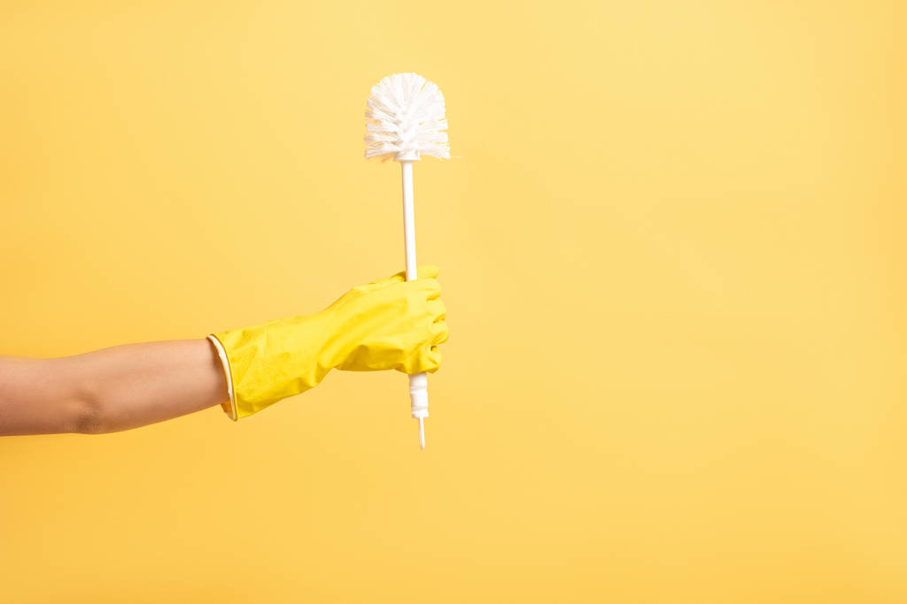Kırpılmış plastik eldivenli kadın pompadan izole edilmiş sarı eldiven tutuyor. - Fotoğraf, Görsel