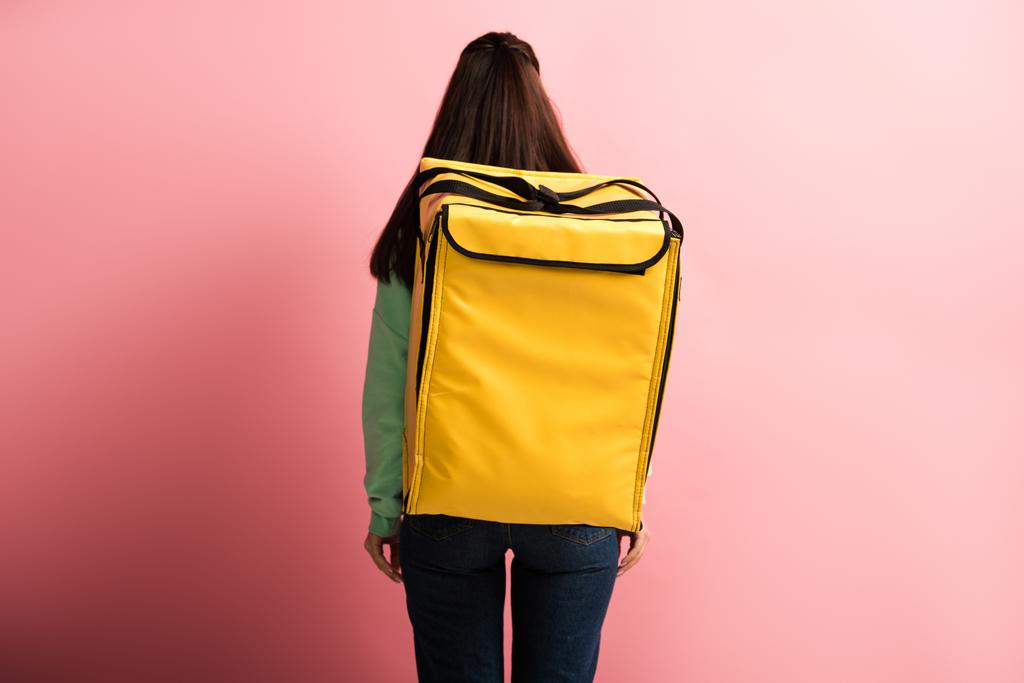 visão traseira da mulher de entrega carregando mochila térmica amarela no fundo rosa
 - Foto, Imagem