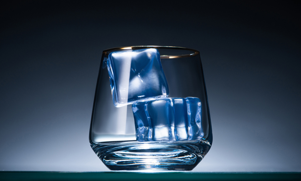 transparentes Glas mit Eiswürfeln in dunkel mit blauer Hintergrundbeleuchtung - Foto, Bild