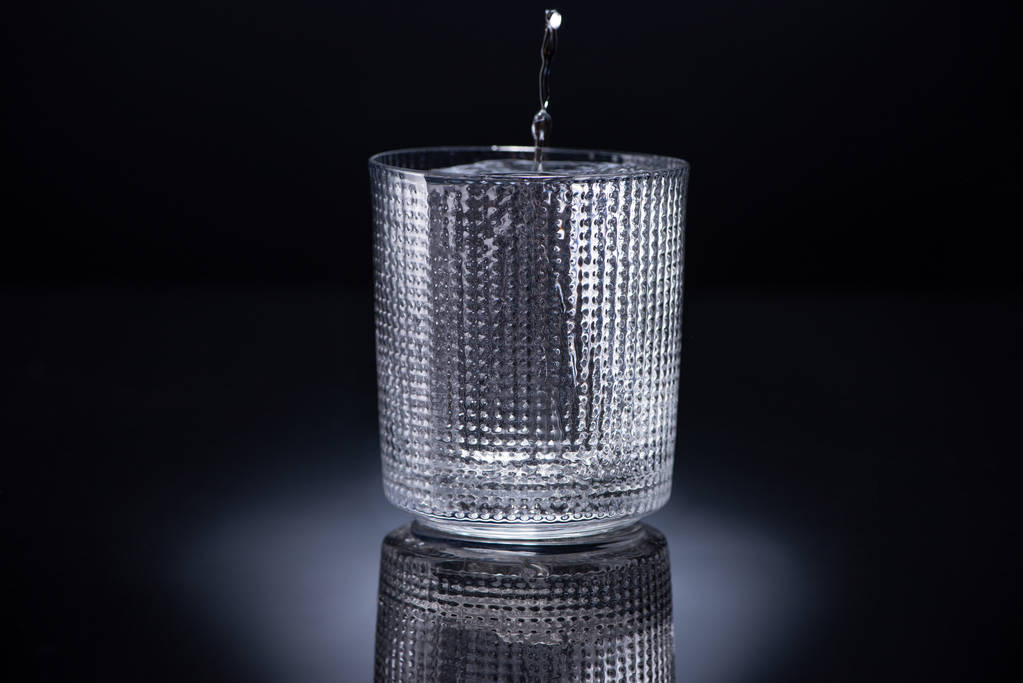 puoli lasi jäällä ja kaatamalla vodkaa mustalla pohjalla
 - Valokuva, kuva