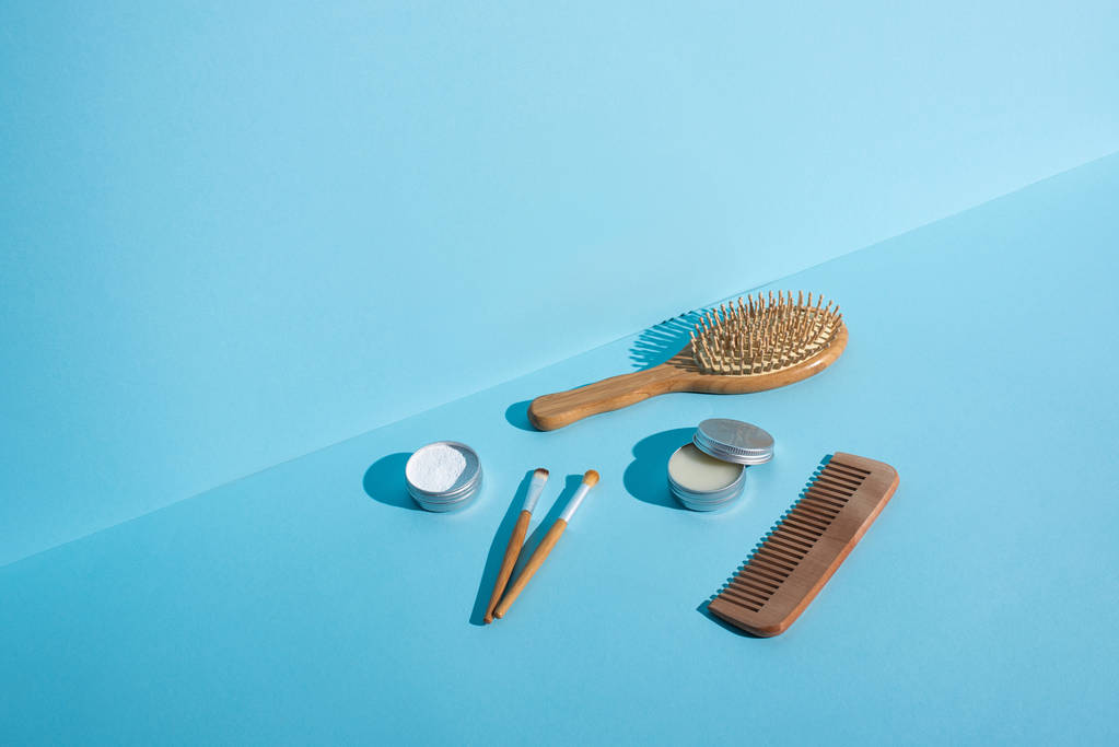Hair brush, comb, jars of wax and tooth powder, cosmetic brushes on blue background, zero waste concept - Photo, Image