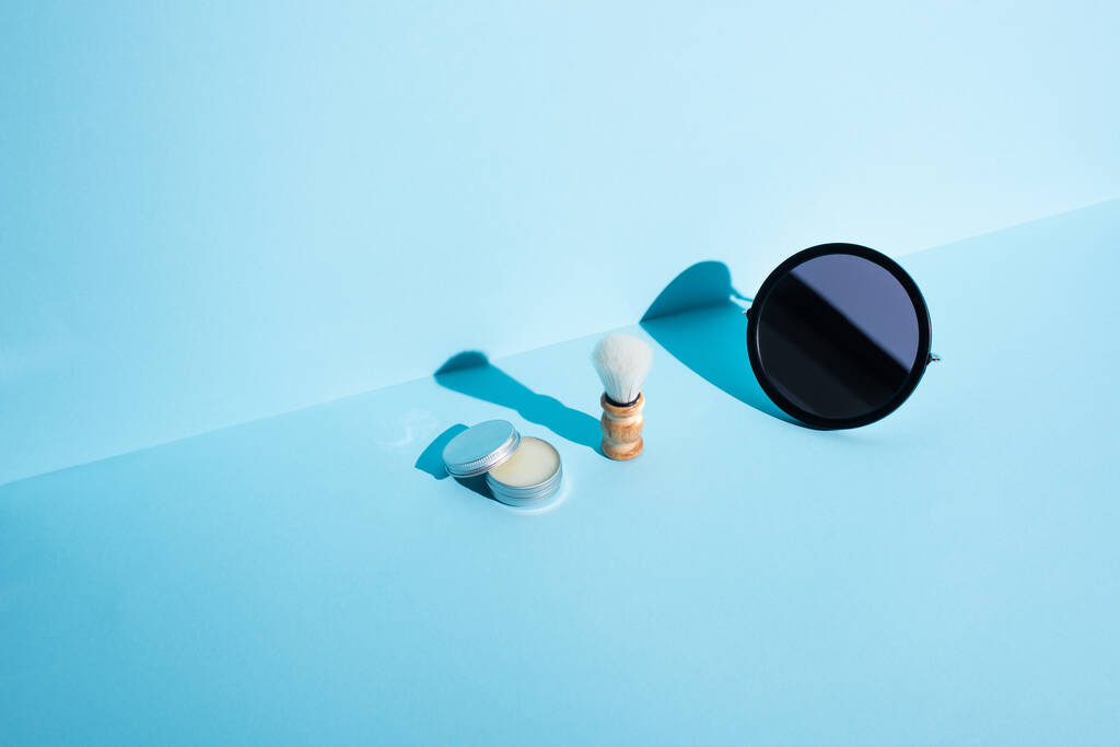Espejo, tarro de cera y cepillo de afeitar sobre fondo azul, concepto de cero residuos
 - Foto, Imagen