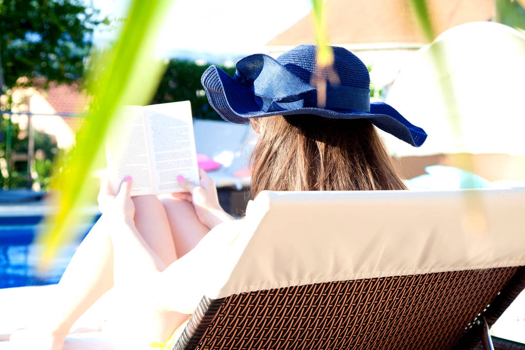 Молодая девушка читает книгу у бассейна
 - Фото, изображение