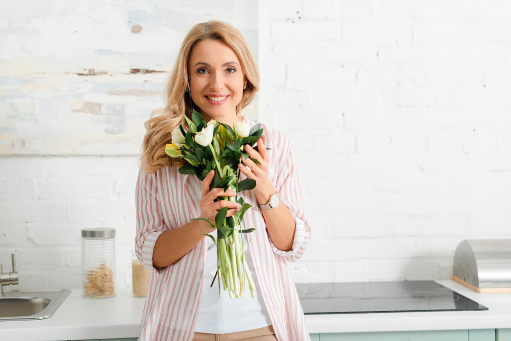 happy woman holding bouquet of tulips at home - Fotoğraf, Görsel
