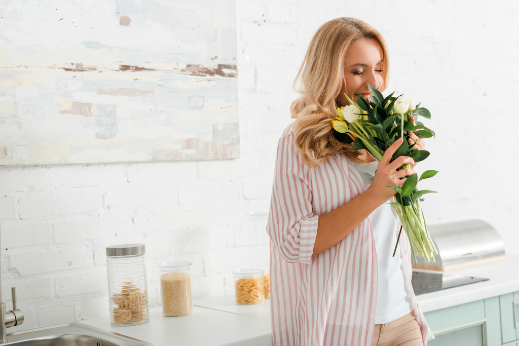 happy woman smelling bouquet of tulips at home - Photo, Image