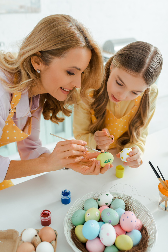 gelukkig moeder en schattig dochter schilderij kip eieren op Pasen  - Foto, afbeelding