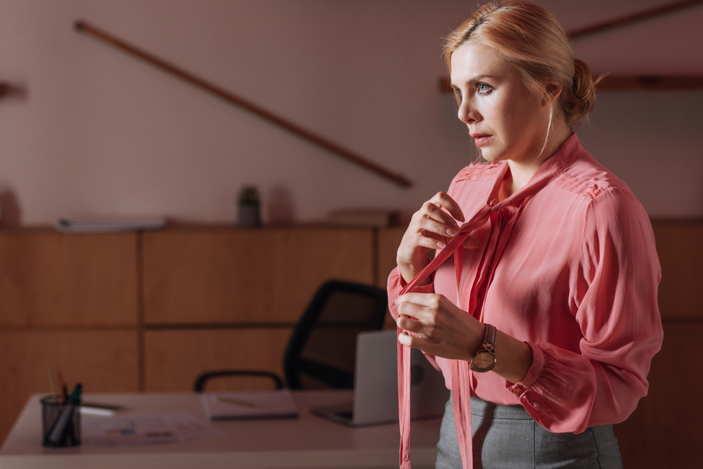 Selective focus of woman untying ribbons on blouse in office, sexual harassment concept - Photo, Image