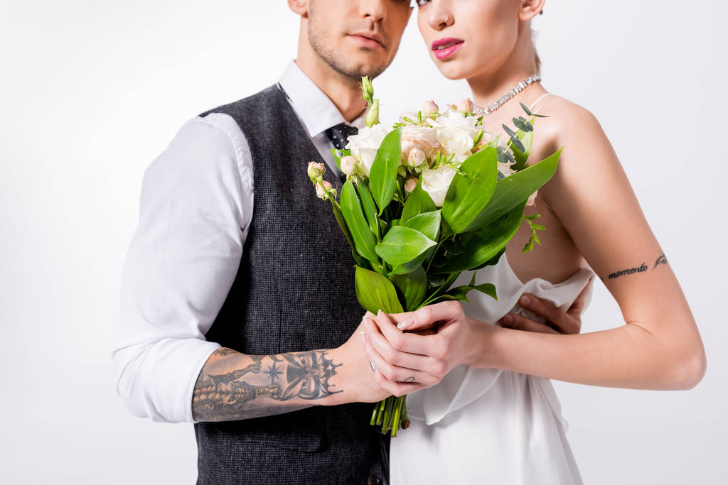 vista recortada de hermosa novia tatuada con ramo y novio guapo aislado en blanco
 - Foto, Imagen