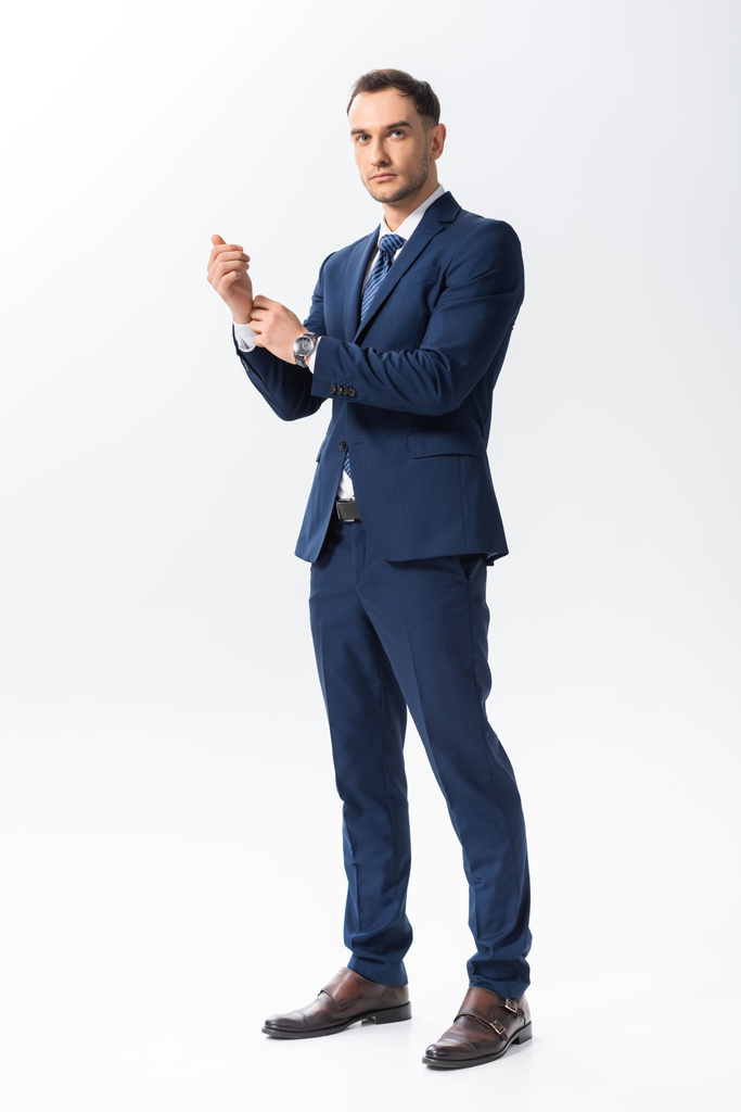 Ganzkörperansicht erfolgreicher junger tätowierter Geschäftsmann im blauen Anzug isoliert auf weißem Grund - Foto, Bild