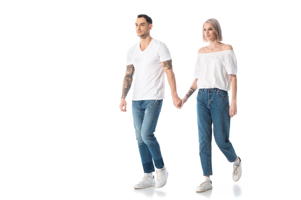 giovane coppia tatuata che si tiene per mano mentre cammina isolata sul bianco
 - Foto, immagini