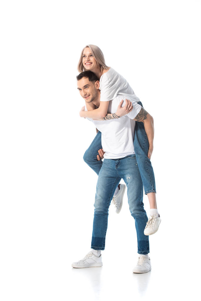 šťastný mladý tetovaný pár piggybacking izolovaný na bílém - Fotografie, Obrázek