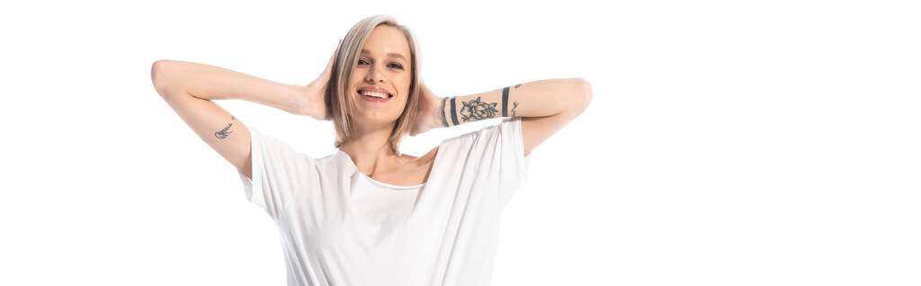 boldog fiatal tetovált lány kezekkel a fején elszigetelt fehér, panorámás lövés - Fotó, kép