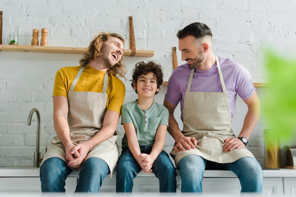 enfoque selectivo de los padres homosexuales felices sonriendo con el hijo de raza mixta
  - Foto, Imagen