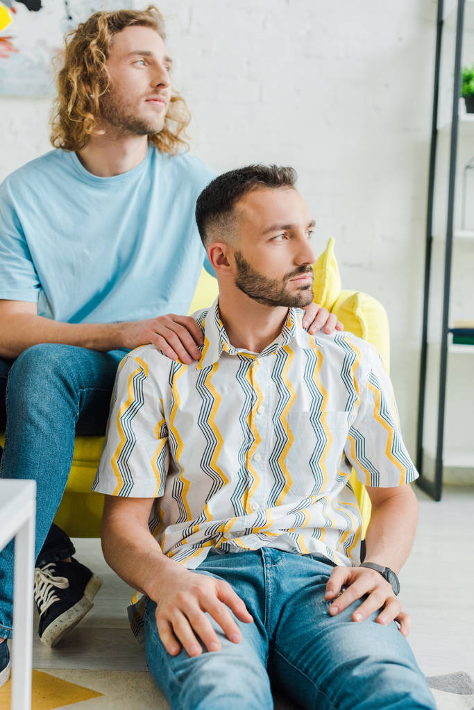 komeat homoseksuaaliset miehet katsovat pois istuessaan olohuoneessa
   - Valokuva, kuva