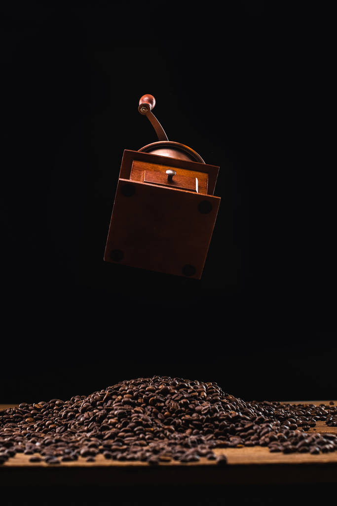 Kaffeemühle über frisch gerösteten Kaffeebohnen isoliert auf schwarz - Foto, Bild