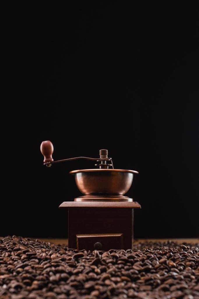 Kahve öğütücüsünün seçici odağı siyah üzerine izole edilmiş taze kavrulmuş kahve çekirdekleri - Fotoğraf, Görsel