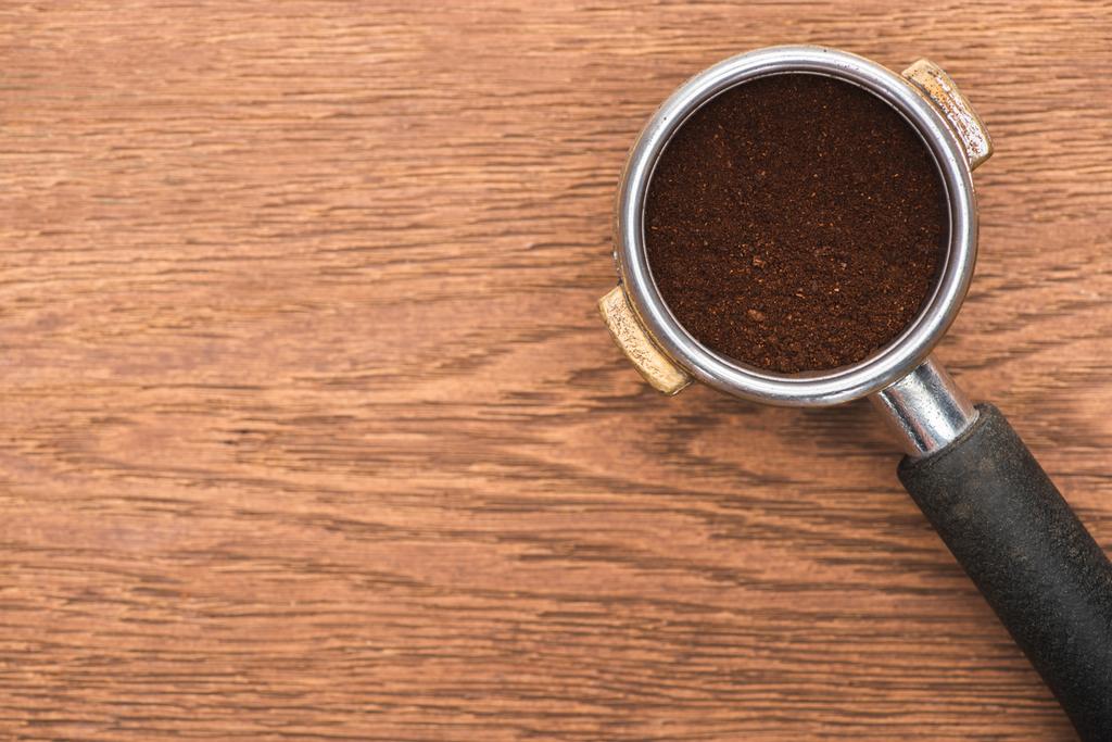 вид зверху свіжих смажених кавових зерен і меленої кави у тримачі фільтрів на дерев'яному столі
 - Фото, зображення