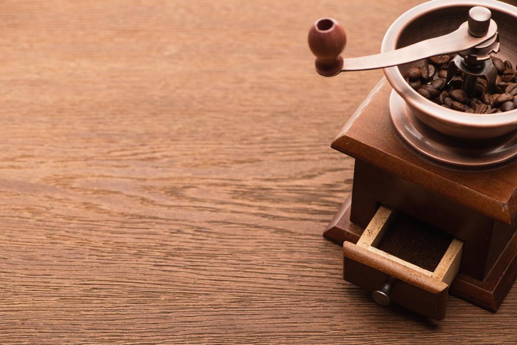 свіжі смажені кавові зерна в кавомолці на дерев'яному столі
 - Фото, зображення
