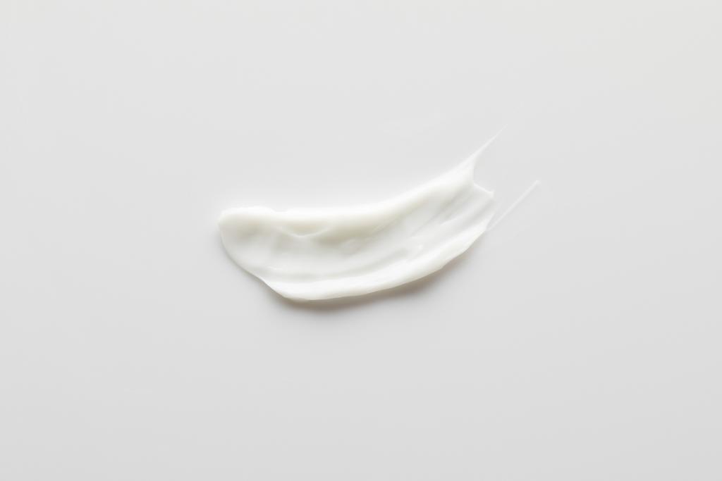 Top view of cosmetic cream brushstroke on grey background - Photo, Image