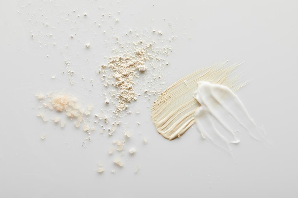 Vue de dessus des coups de pinceau au sel de mer, poudre pour le visage, cosmétique et crème tonique sur fond gris
 - Photo, image