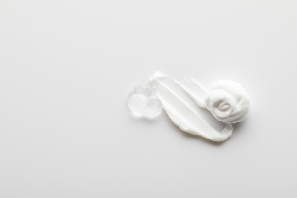 Vista superior de pinceladas de crema cosmética con gel sobre fondo gris
 - Foto, imagen