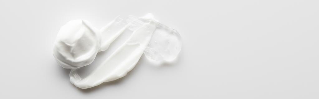  Vista superior de la crema cosmética pinceladas y gel sobre fondo gris, plano panorámico
 - Foto, Imagen