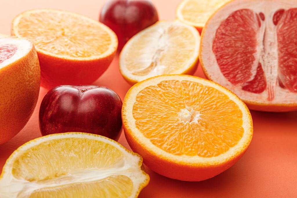 Enfoque selectivo de mitades de cítricos y manzanas sobre fondo colorido
 - Foto, imagen