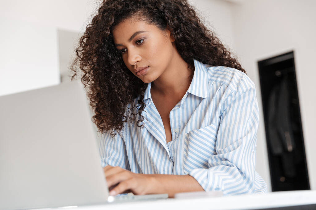 Jovem mulher africana atraente trabalhando no computador portátil
 - Foto, Imagem
