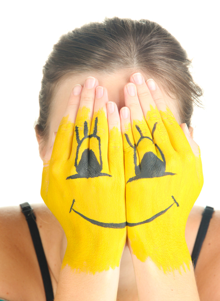 Porträt eines Mädchens, das sein Gesicht unter einer Lächeln-Maske versteckt - Foto, Bild