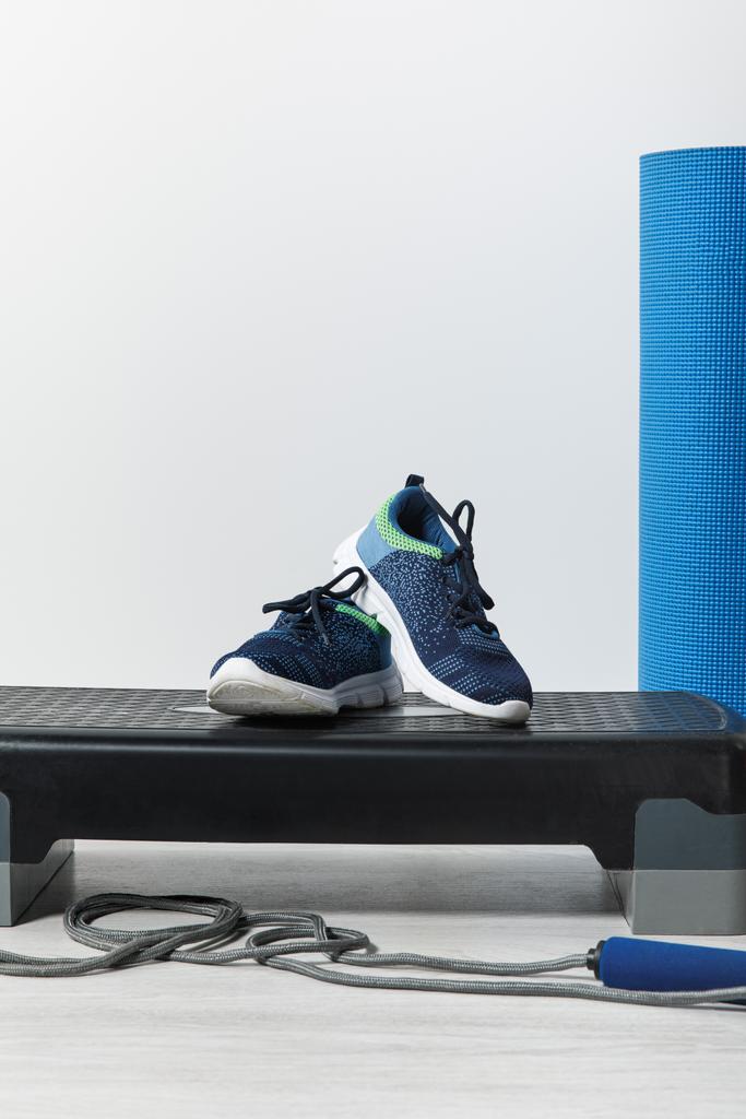 plataforma paso, alfombra de fitness azul, saltar la cuerda y zapatillas de deporte en el suelo en casa
  - Foto, Imagen