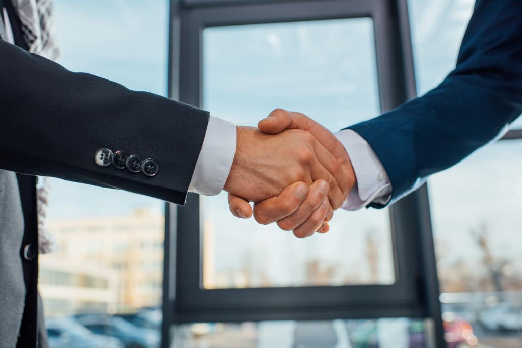 visão cortada de empresários apertando as mãos em reunião no escritório
 - Foto, Imagem