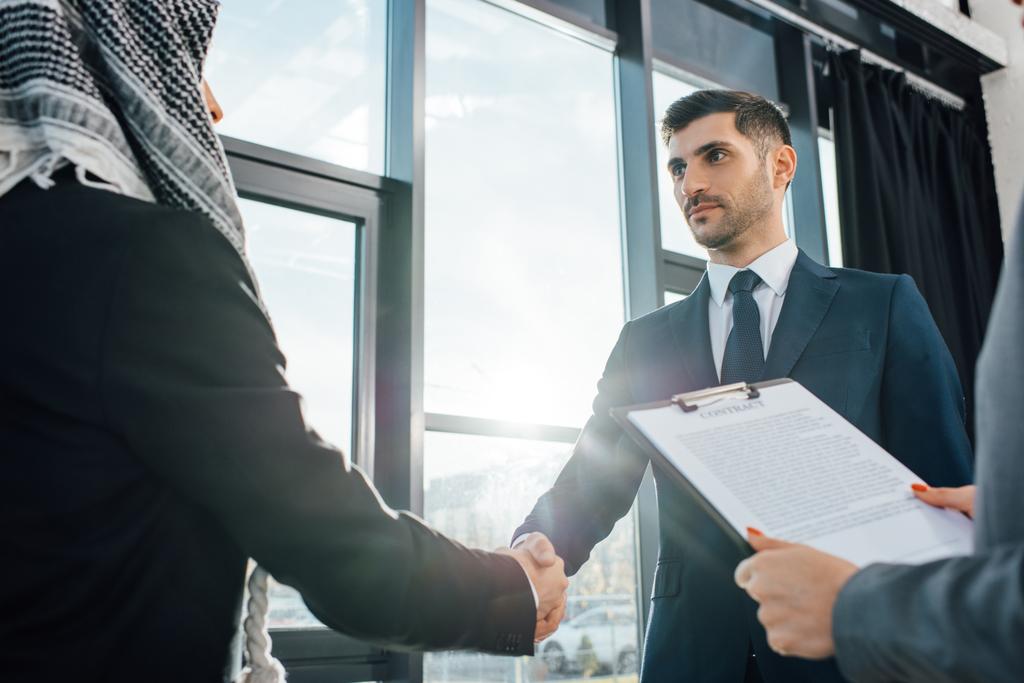 Арабический бизнесмен пожимает руку партнеру на встрече с переводчиком в офисе
 - Фото, изображение