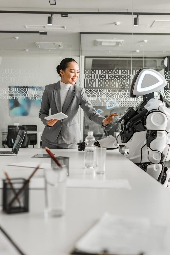 ελκυστική Ασιάτισσα επιχειρηματίας που χειρίζεται ρομπότ ενώ κρατά ψηφιακή ταμπλέτα - Φωτογραφία, εικόνα