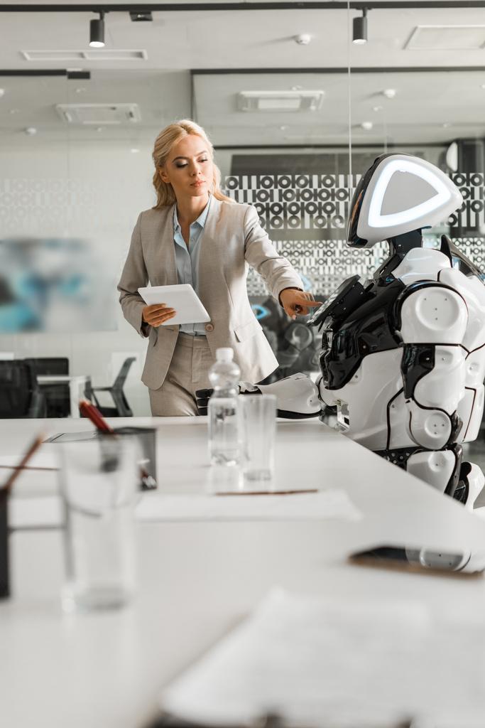 вибірковий фокус привабливої бізнес-леді, що керує роботом, тримаючи цифровий планшет
 - Фото, зображення