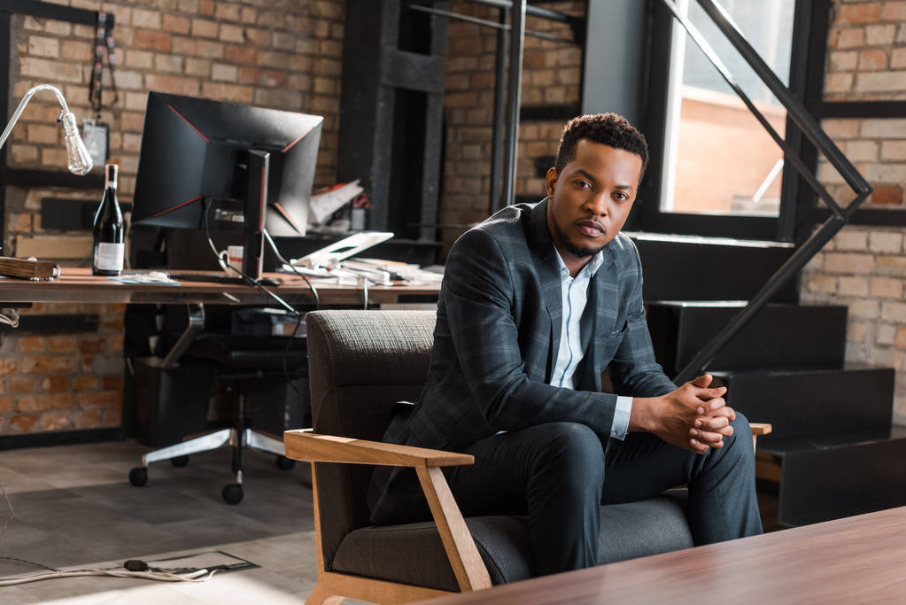 αυτοπεποίθηση Αφροαμερικανός επιχειρηματίας κάθεται στην πολυθρόνα και κοιτάζοντας την κάμερα - Φωτογραφία, εικόνα