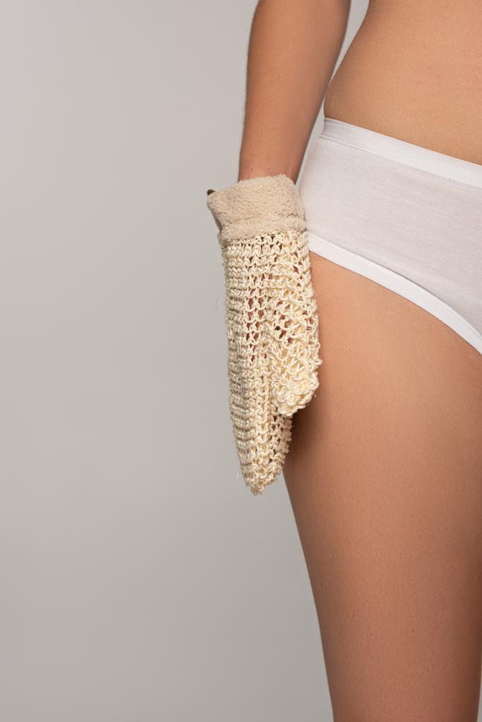 abgeschnittene Ansicht einer Frau mit perfekter Haut mit Peelinghandschuh, isoliert auf grau - Foto, Bild