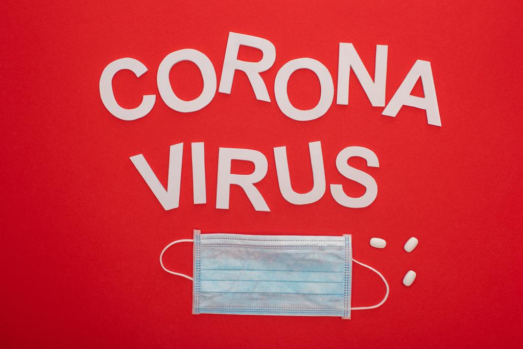 Vista dall'alto del coronavirus lettering, maschera medica e pillole isolate sul rosso
 - Foto, immagini