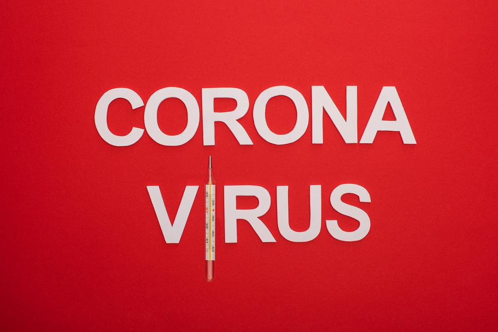 Vista superior de letras coronavírus com termômetro isolado em vermelho
 - Foto, Imagem