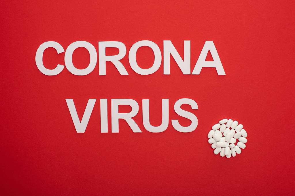 Vue du dessus des pilules et du lettrage du coronavirus sur fond rouge
 - Photo, image