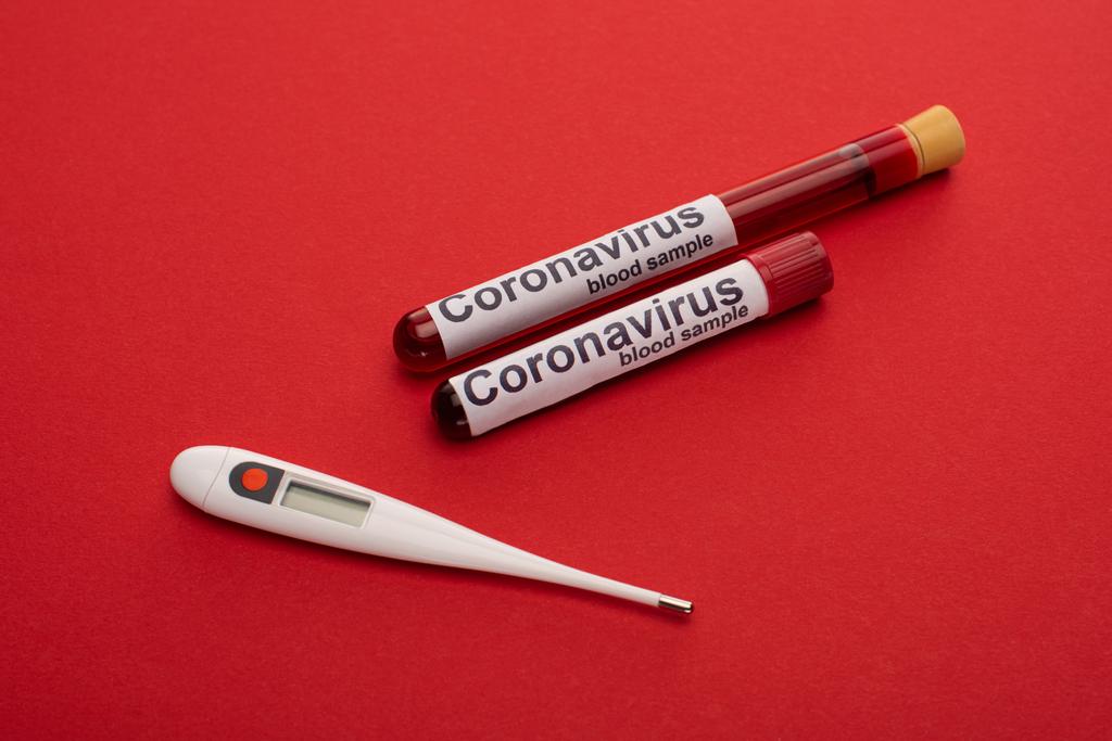 Крупный план термометра, пробирки с образцами крови и коронавирусом на красном фоне
 - Фото, изображение