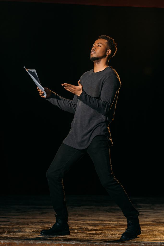 actor afroamericano sosteniendo escenario y de pie en el escenario durante el ensayo en el teatro
 - Foto, imagen