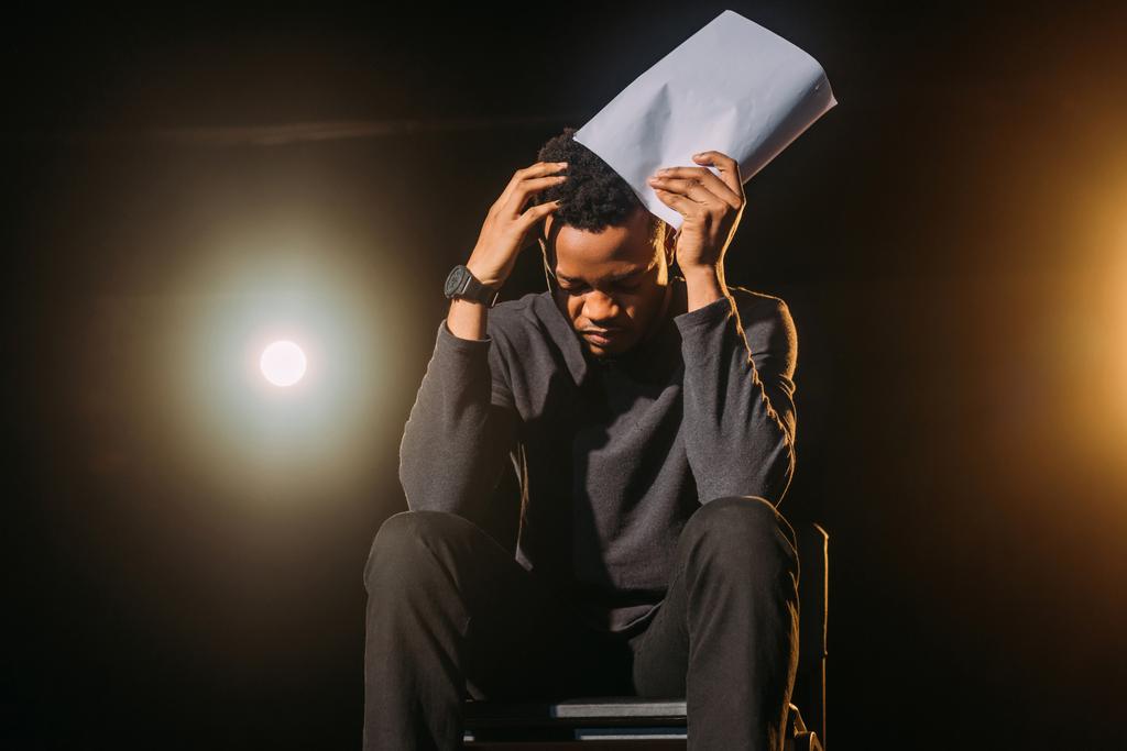 estressado ator afro-americano segurando cenário no palco durante o ensaio
  - Foto, Imagem