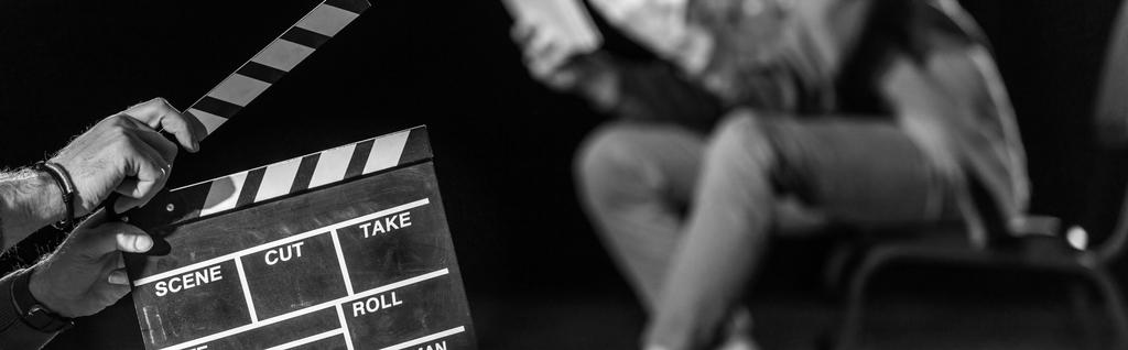 panoramic shot of actor with clapperboard in front, isolated on black, black and white - Photo, Image