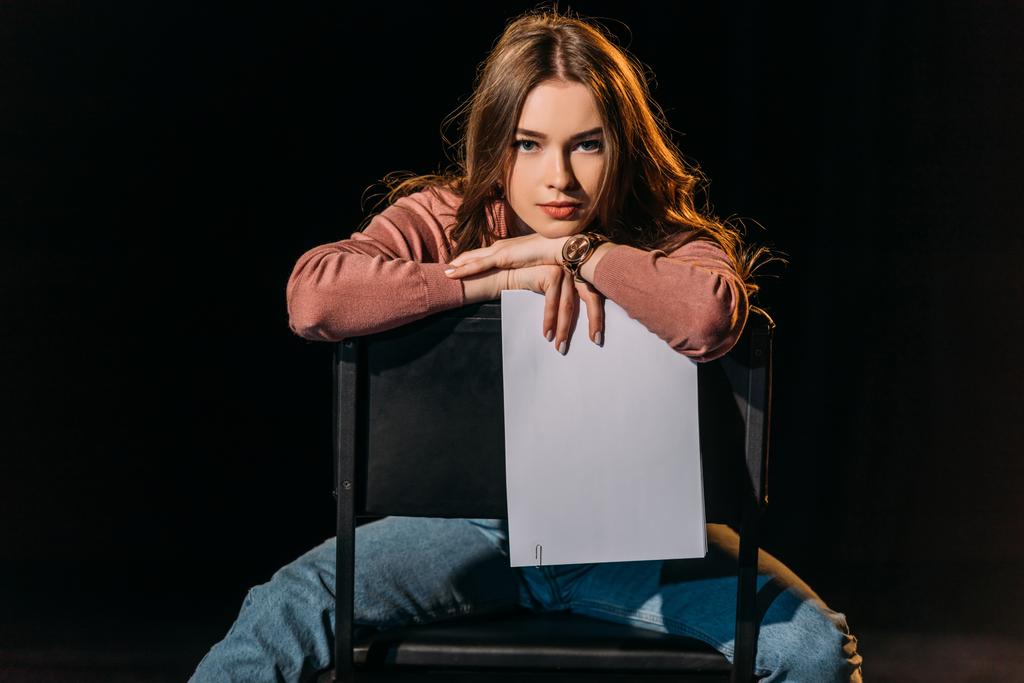 attractive young actress with scenario sitting on chair on stage in theatre - Photo, Image