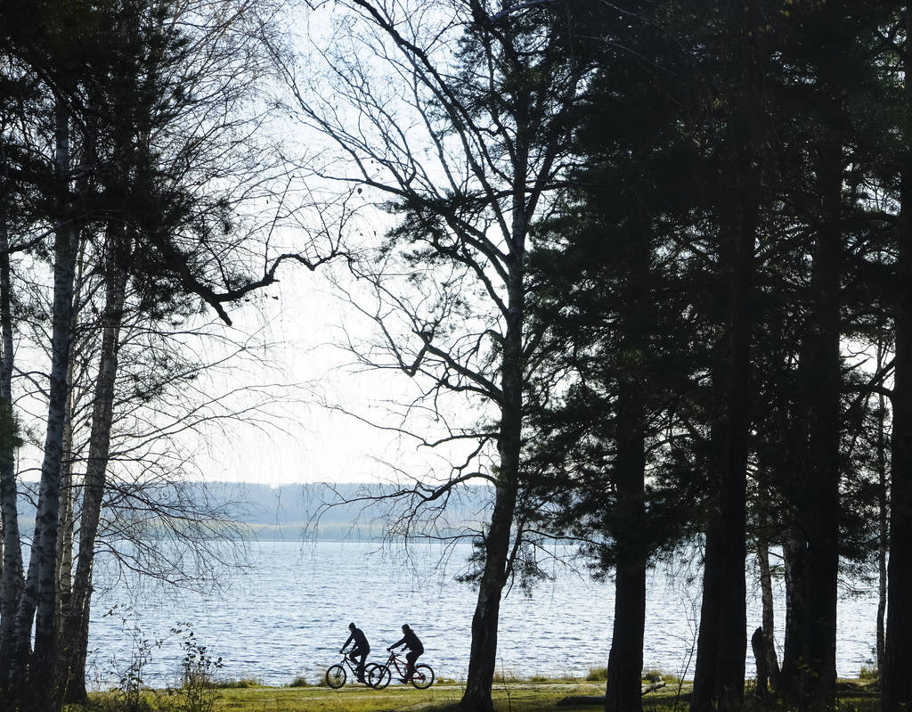 Bisiklet süren turist çift. Kadın ve erkek yeşil ormanlık ve su kanalları arasında bisiklet sürerken eğleniyorlar. Nehir boyunca bisiklet süren kadın ve erkek.. - Fotoğraf, Görsel