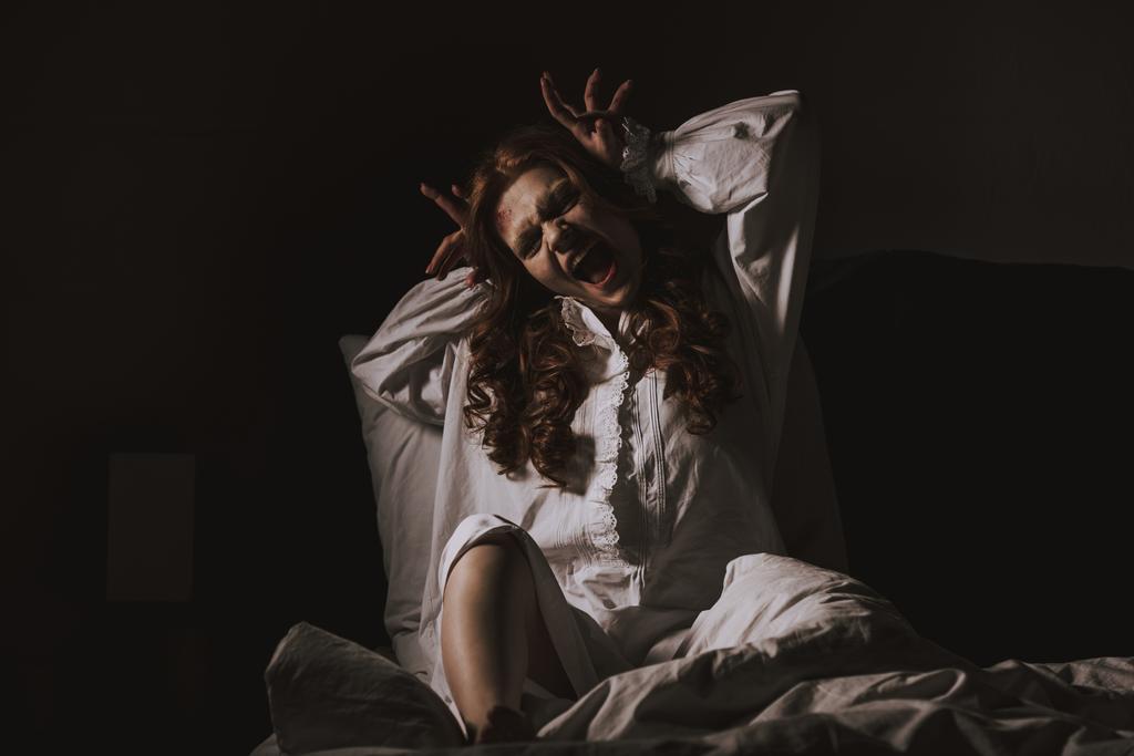 obsesyjnie przerażająca dziewczyna w koszuli nocnej gestykulując i krzycząc w sypialni - Zdjęcie, obraz